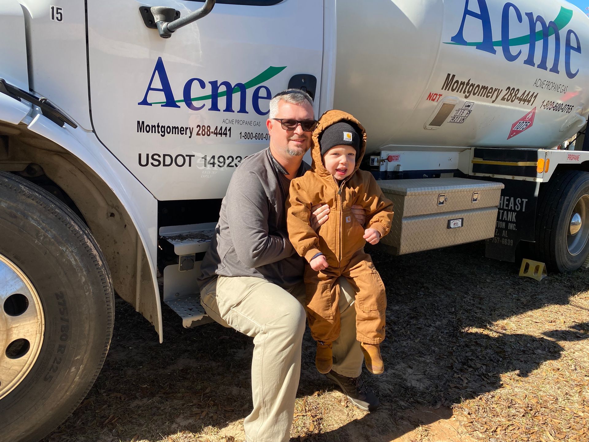 A man and a child are sitting on the back of a truck.