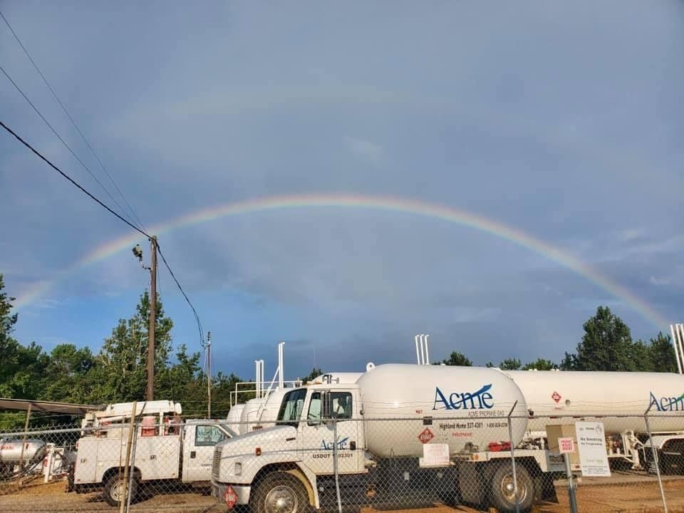 A rainbow is visible over a fuel truck in a parking lot.