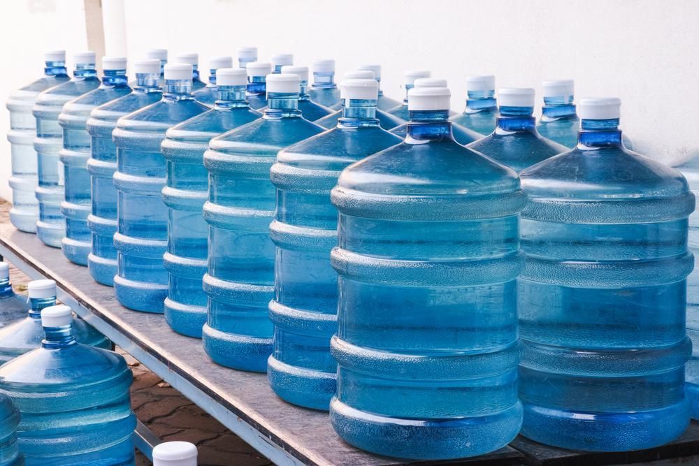 A Row of Water Bottles Sitting on Top of A Wooden Table — Cool Blue Ice & Water in Mudgee, NSW