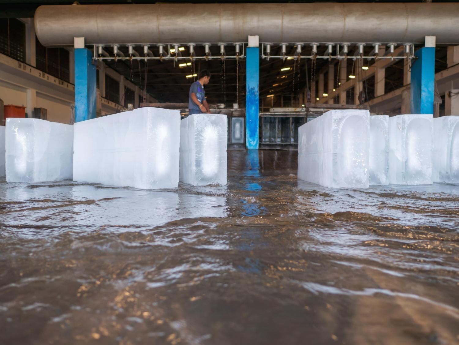 A Man Is Standing in A Flooded Room Surrounded by Ice Cubes — Cool Blue Ice & Water in Taminda, NSW