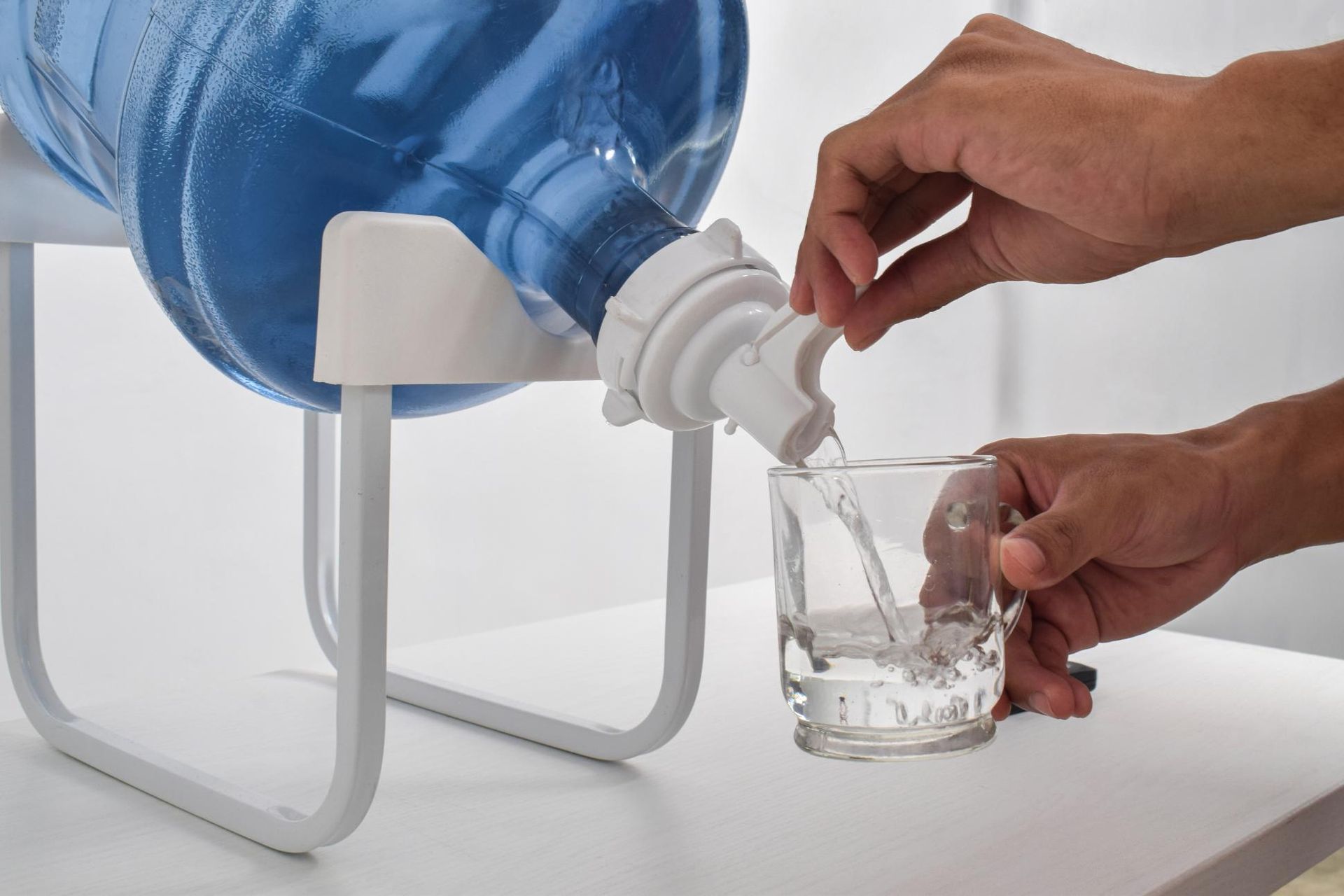 A Person Is Pouring Water from A Bottle Into a Glass — Cool Blue Ice & Water in Walgett, NSW