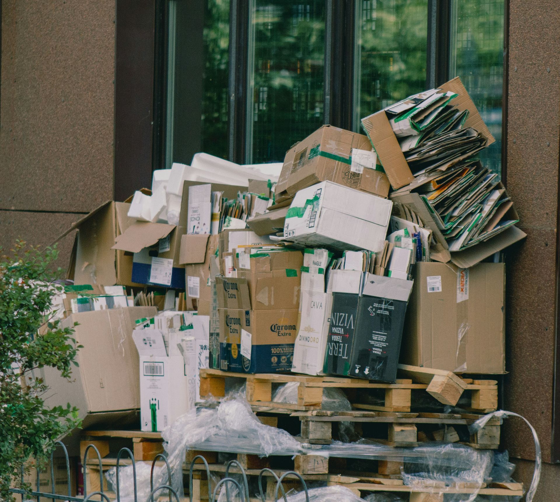 Large pile of cardboard boxes and packages stacked beside a building window