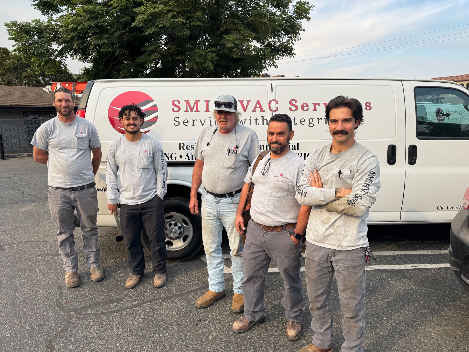 Five workers stand in front of a white van with "Smith Vac Services" logo. They wear work clothes; one has crossed arms.