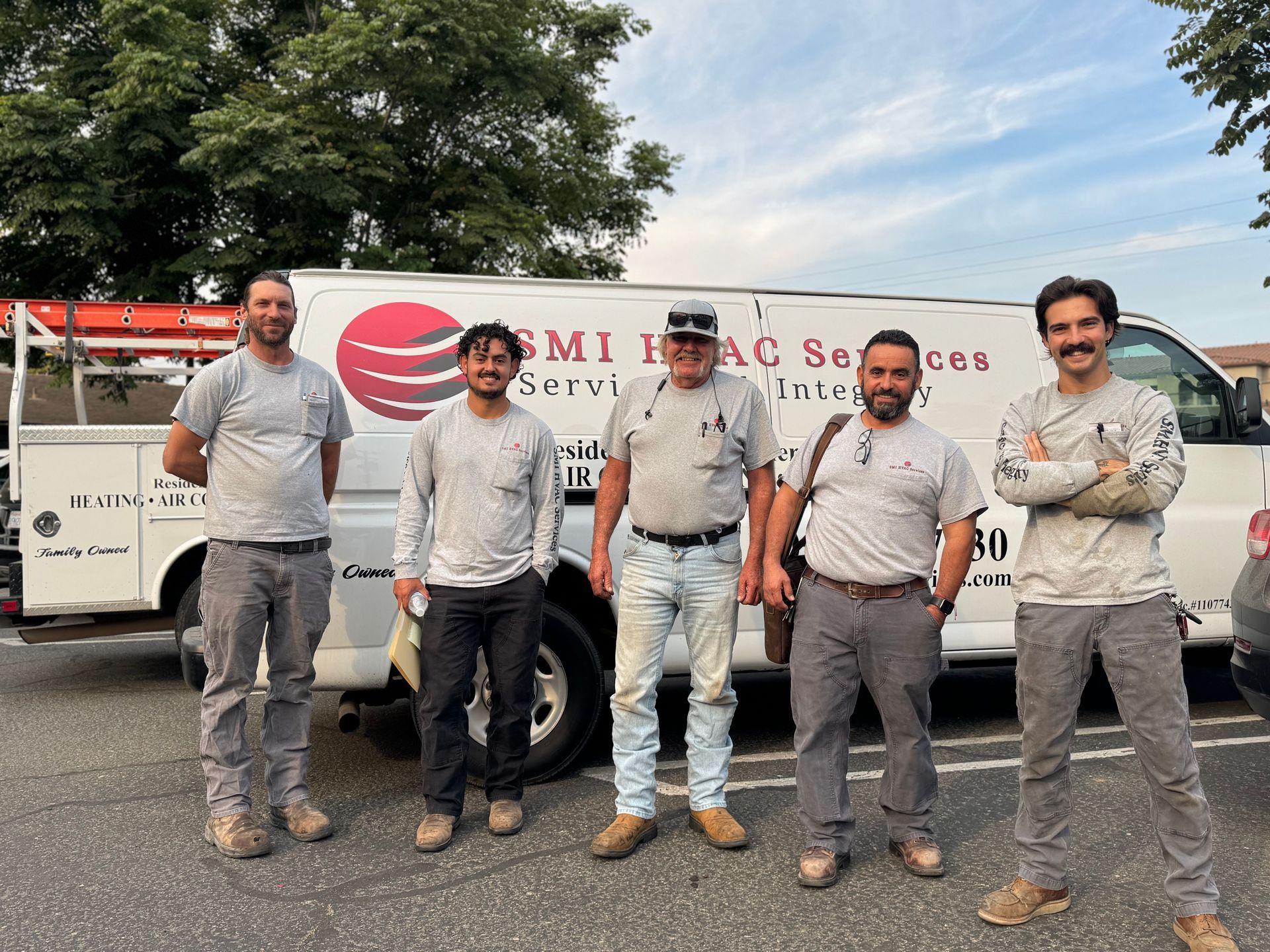 Five men stand in front of a white van with "SMI HVAC Services" logo on it.