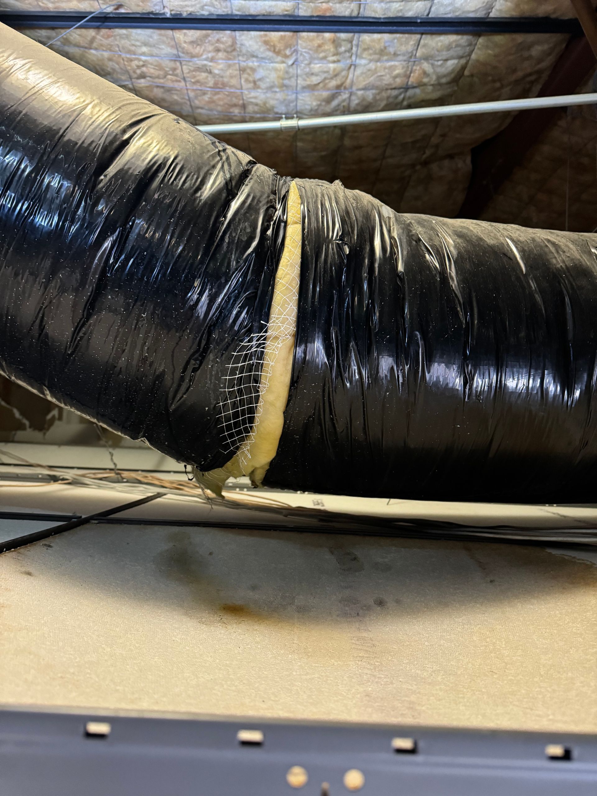 Man in mask and gloves, replacing air filter in ceiling.