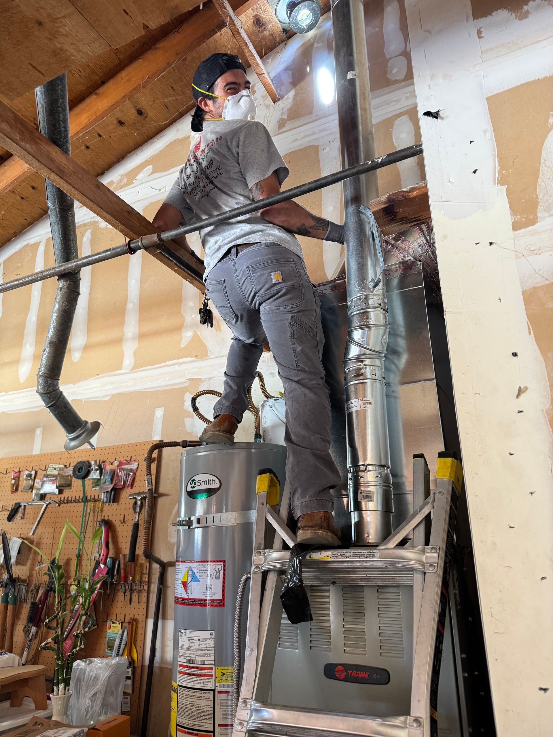 Person on a ladder cutting a metal pipe indoors. Sparks fly.