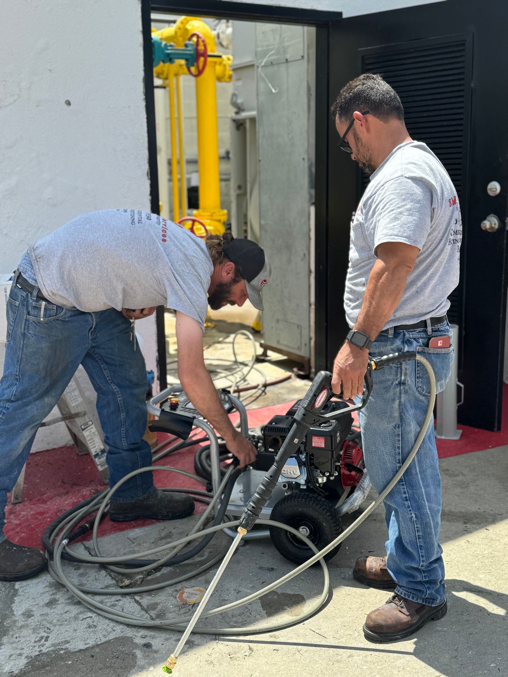 Technician in a light blue uniform inspecting ceiling air conditioner unit, holding a clipboard.