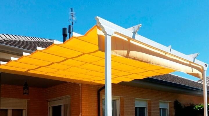 Un toldo amarillo está encima de una casa de ladrillos.