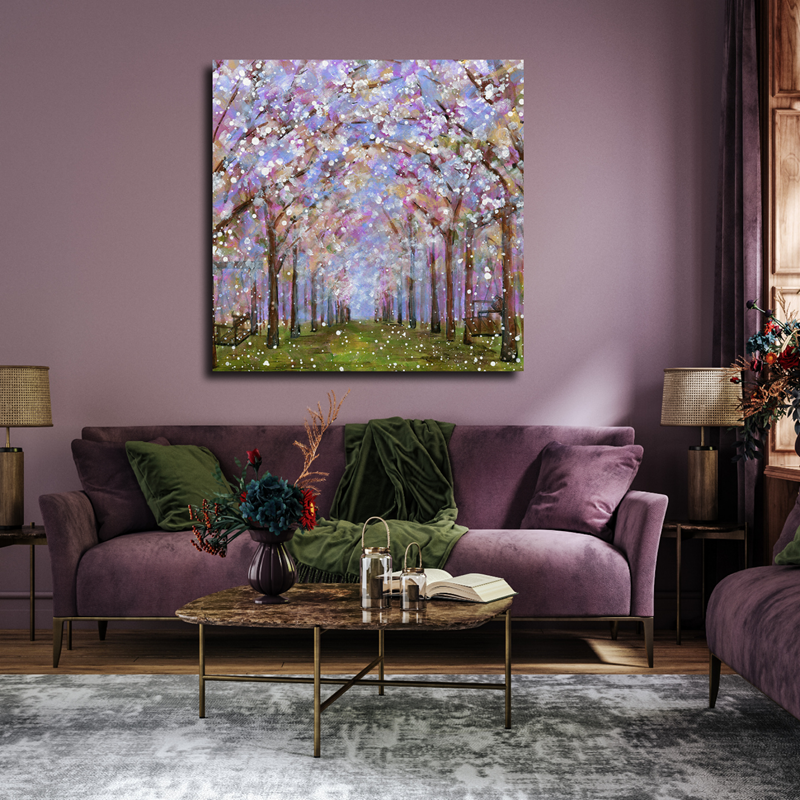 Room with a purple couch, painting of a flowering tree-lined path, and other decor.