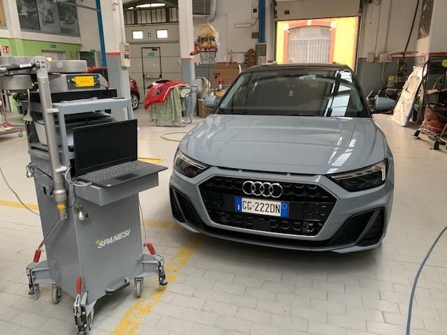 Un operaio edile con un guanto giallo tiene in mano una bobina di filo bianco, mentre nella sua cintura da lavoro si intravedono gli attrezzi.