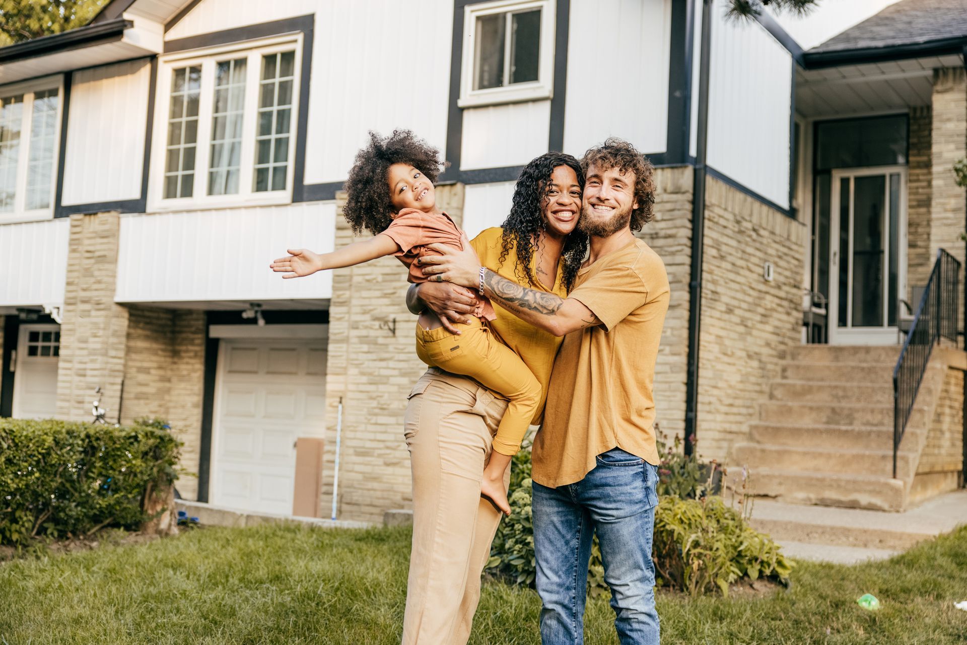 A smiling family standing in their front yard, showcasing reliable home insurance.