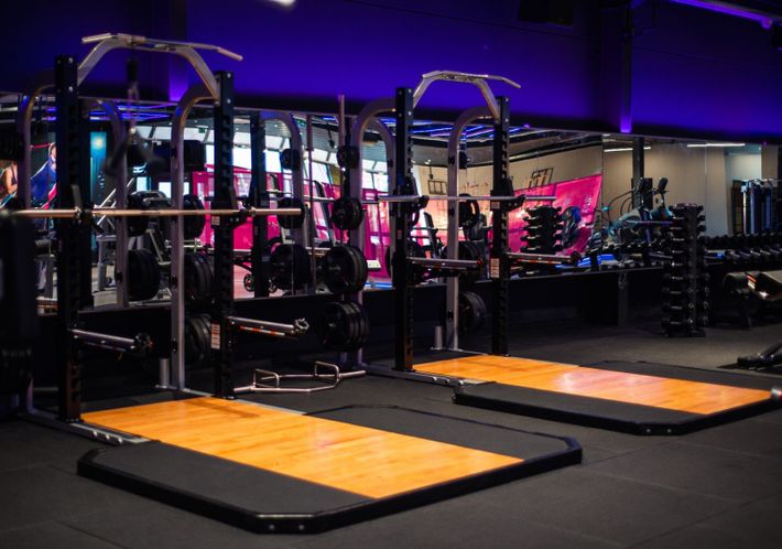 een fitnessruimte met veel apparatuur en een houten vloer.