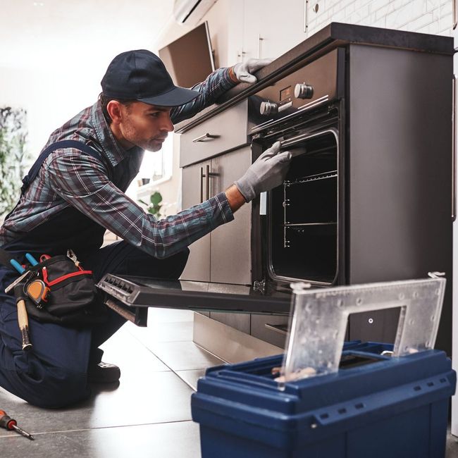 technician repairing oven appliance for homeowners