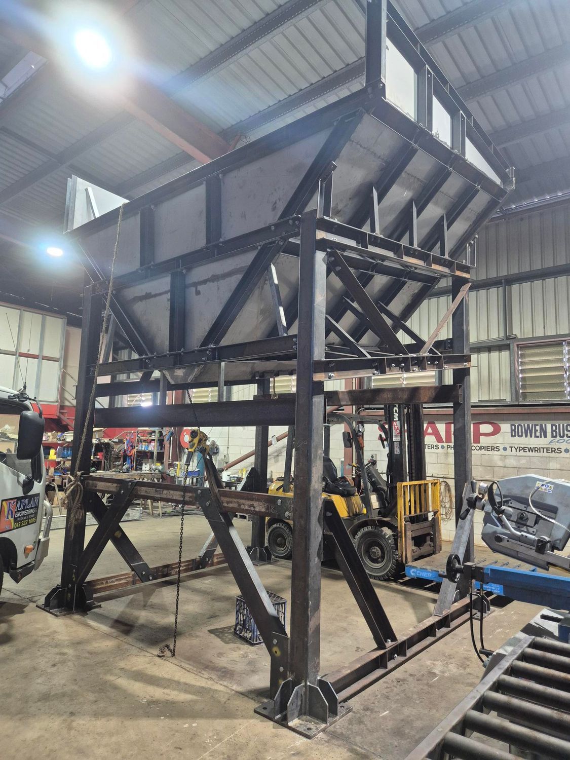 Large Black Industrial Metal Hopper Frame Inside a Warehouse, With Forklifts — Kaplan Engineering Pty Ltd In Bowen, QLD