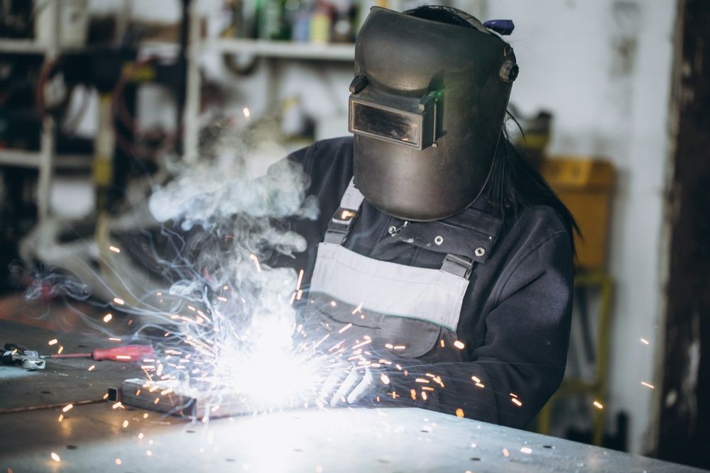 A Woman Is Welding A Piece Of Metal In A Garage — Kaplan Engineering Pty Ltd In Bowen, QLD