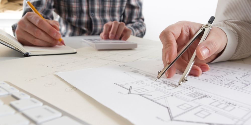 A Man Is Using A Compass To Draw A House On A Piece Of Paper — Kaplan Engineering Pty Ltd In Bowen, QLD