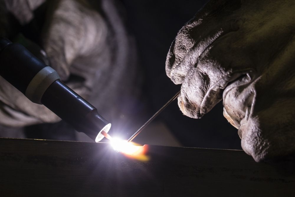 A Person Is Welding A Piece Of Metal In A Dark Room — Kaplan Engineering Pty Ltd In Airlie Beach, QLD
