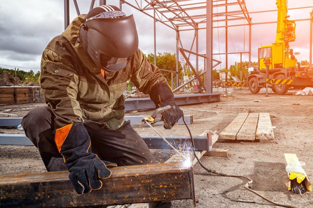 A Man Is Welding A Piece Of Metal On A Construction Site — Kaplan Engineering Pty Ltd In Airlie Beach, QLD