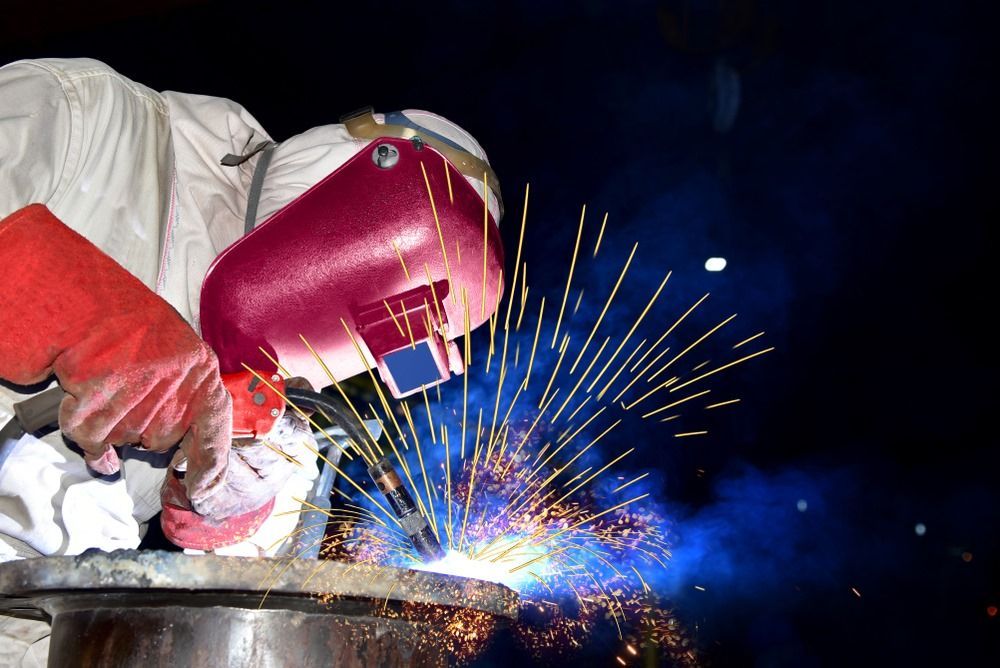A Man Wearing A Welding Mask Is Welding A Piece Of Metal — Kaplan Engineering Pty Ltd In Collinsville, QLD