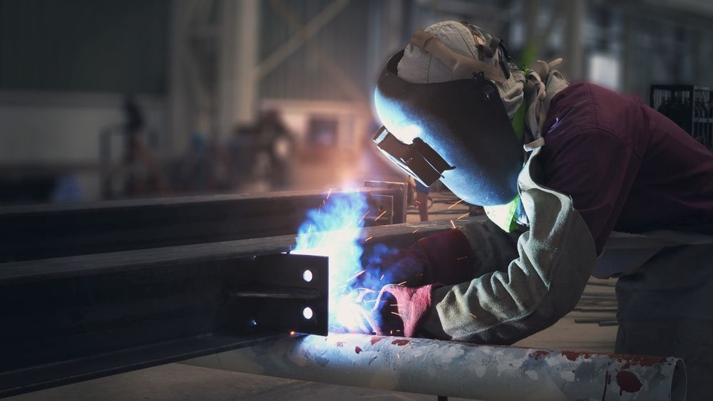 A Man Is Welding A Piece Of Metal In A Factory — Kaplan Engineering Pty Ltd In Collinsville, QLD