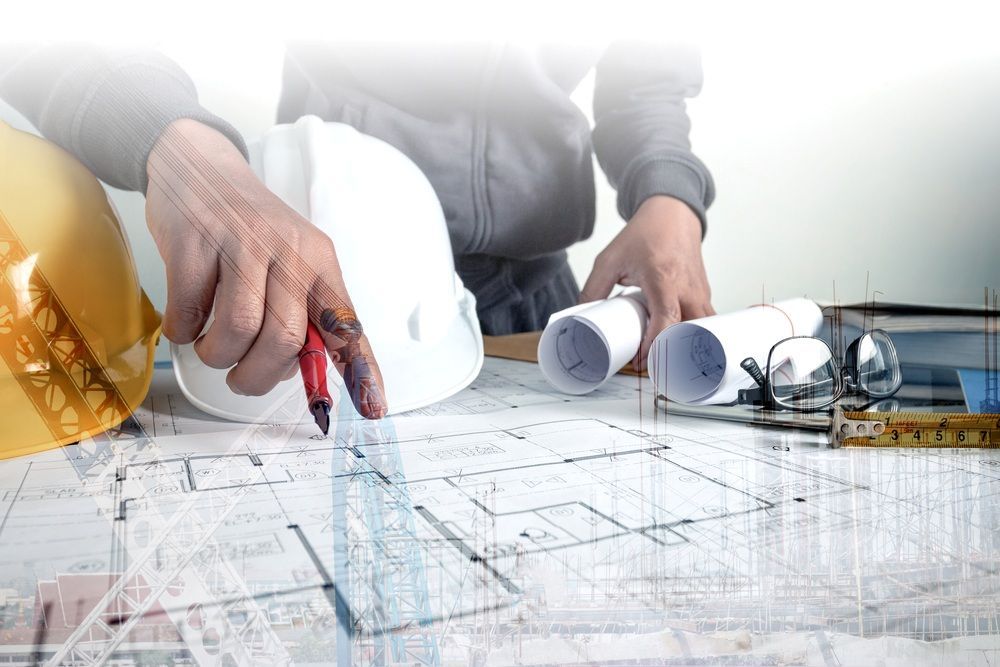 A Man Is Drawing A Blueprint With A Compass And A Hard Hat — Kaplan Engineering Pty Ltd In Bowen, QLD
