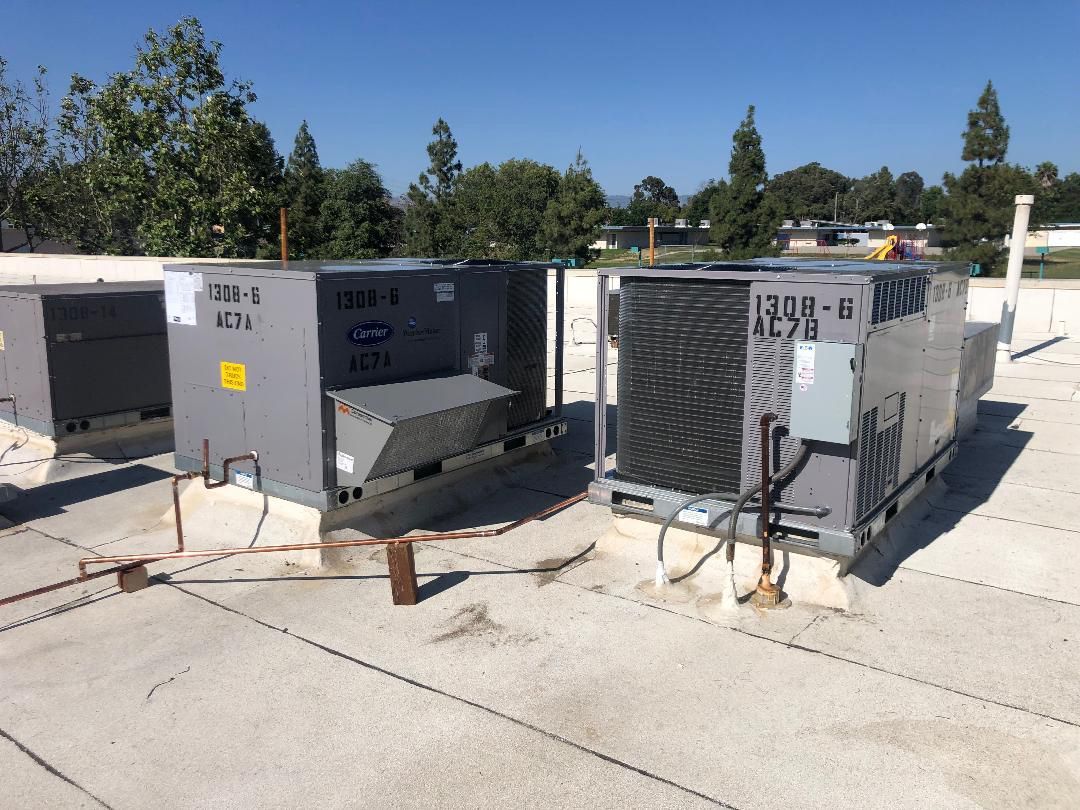 There are two air conditioners on the roof of a building.