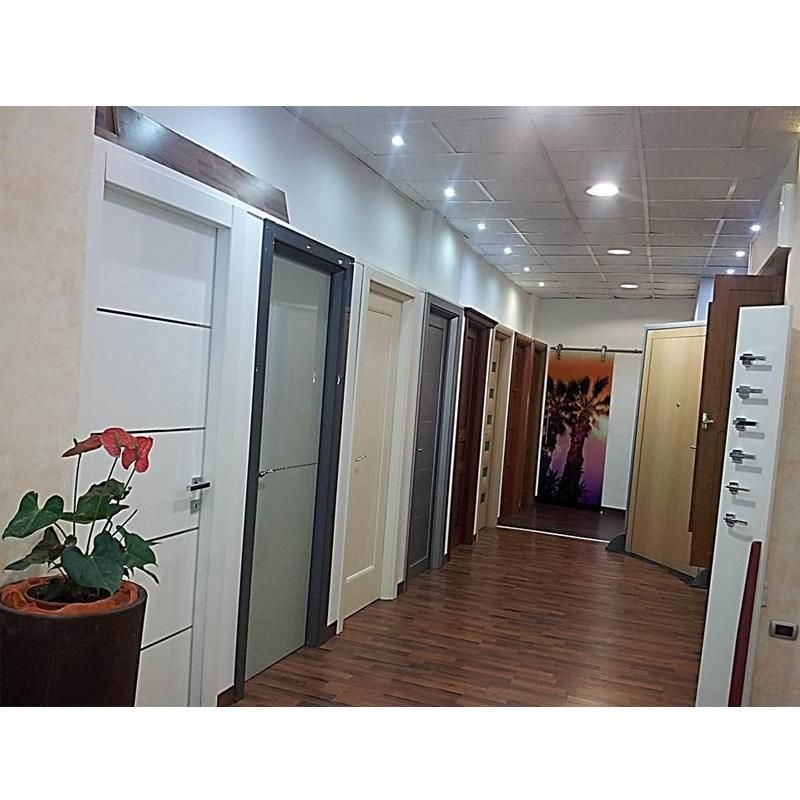 Showroom di porte per interni con vari stili e colori esposti su pavimento in legno.