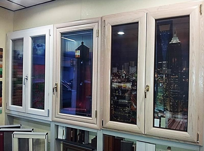 Quattro vetrine che mostrano paesaggi urbani notturni e dettagli architettonici, in uno showroom.