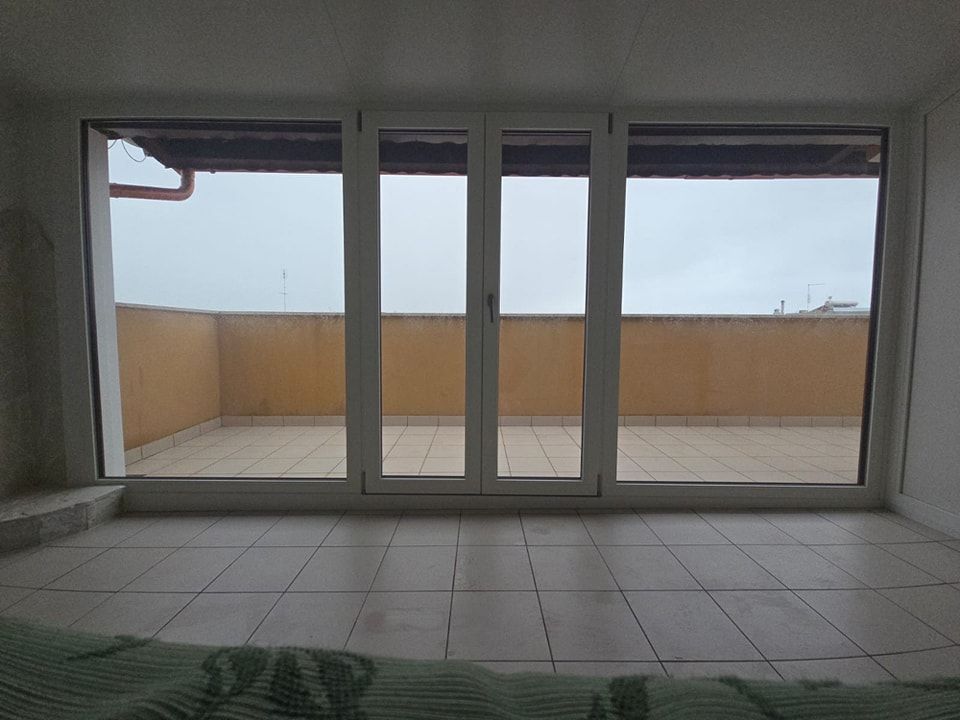 Una stanza con una grande finestra e un balcone visibile attraverso di essa nelle giornate nuvolose.