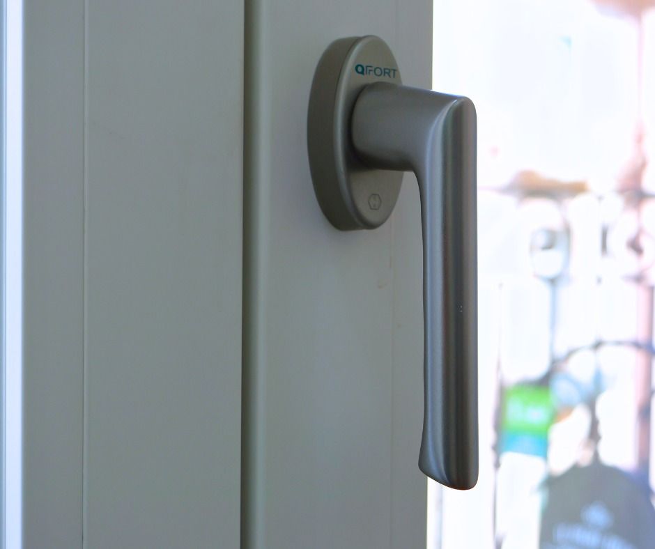 Maniglia per finestra argentata su telaio bianco.