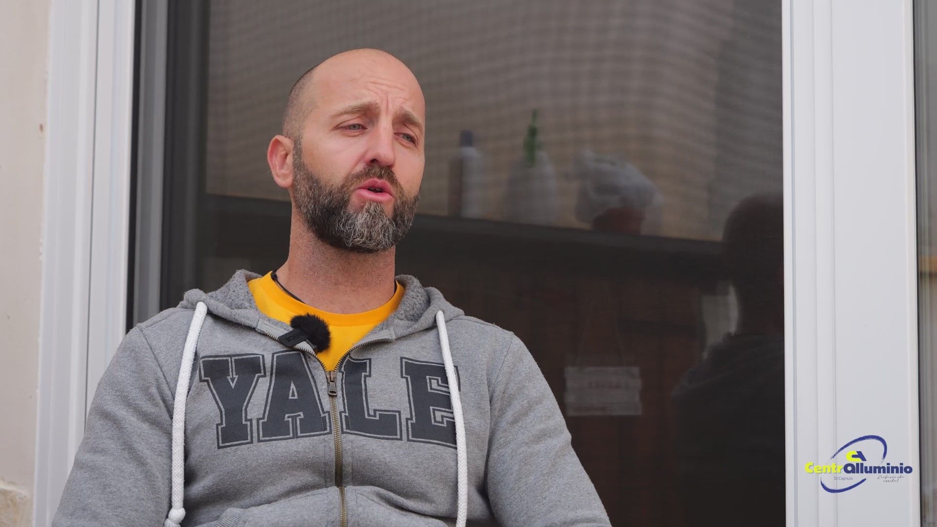 Un uomo con la barba e la felpa con cappuccio di Yale parla all'esterno.