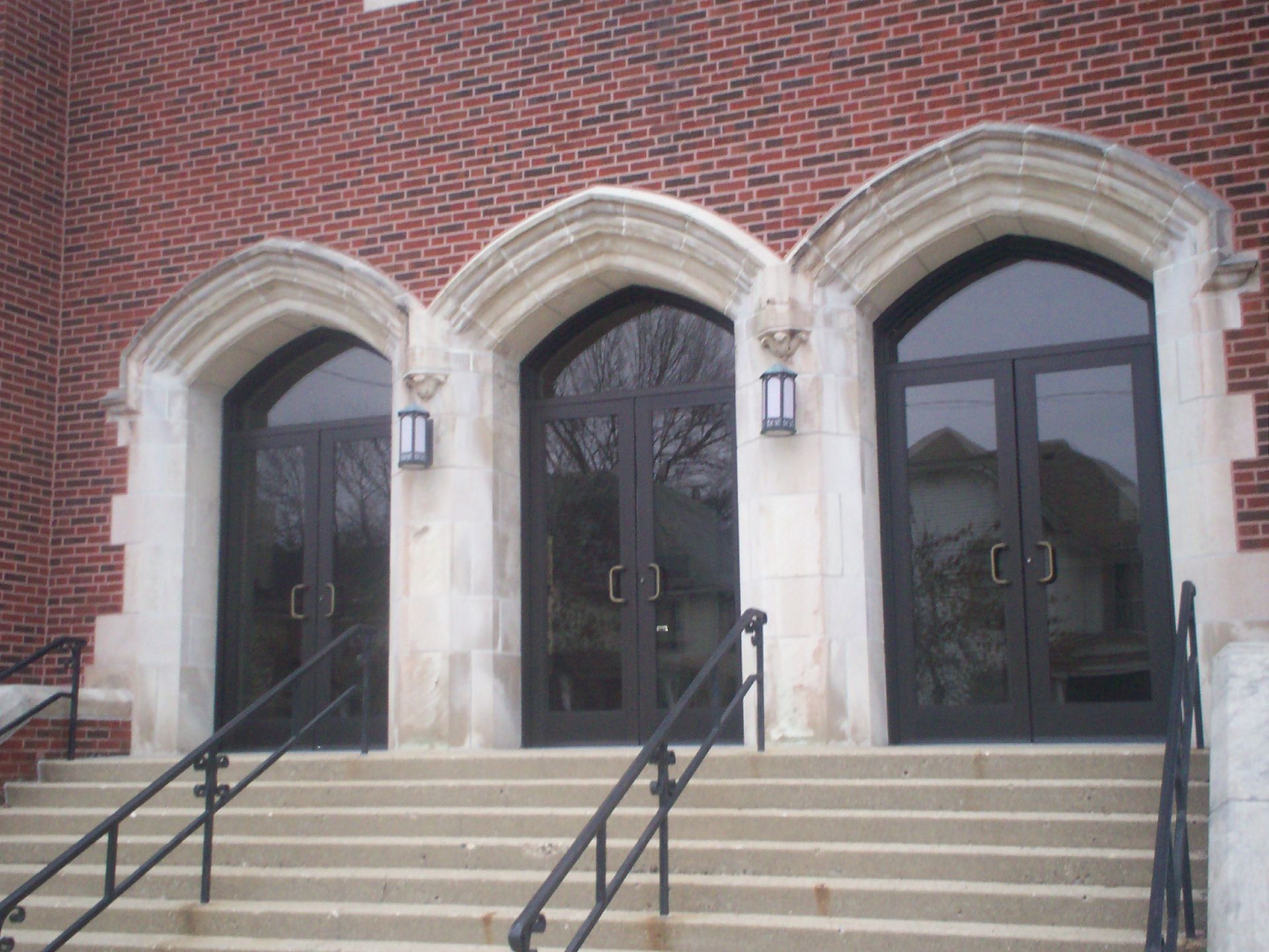 A brick building with three arched doors and stairs