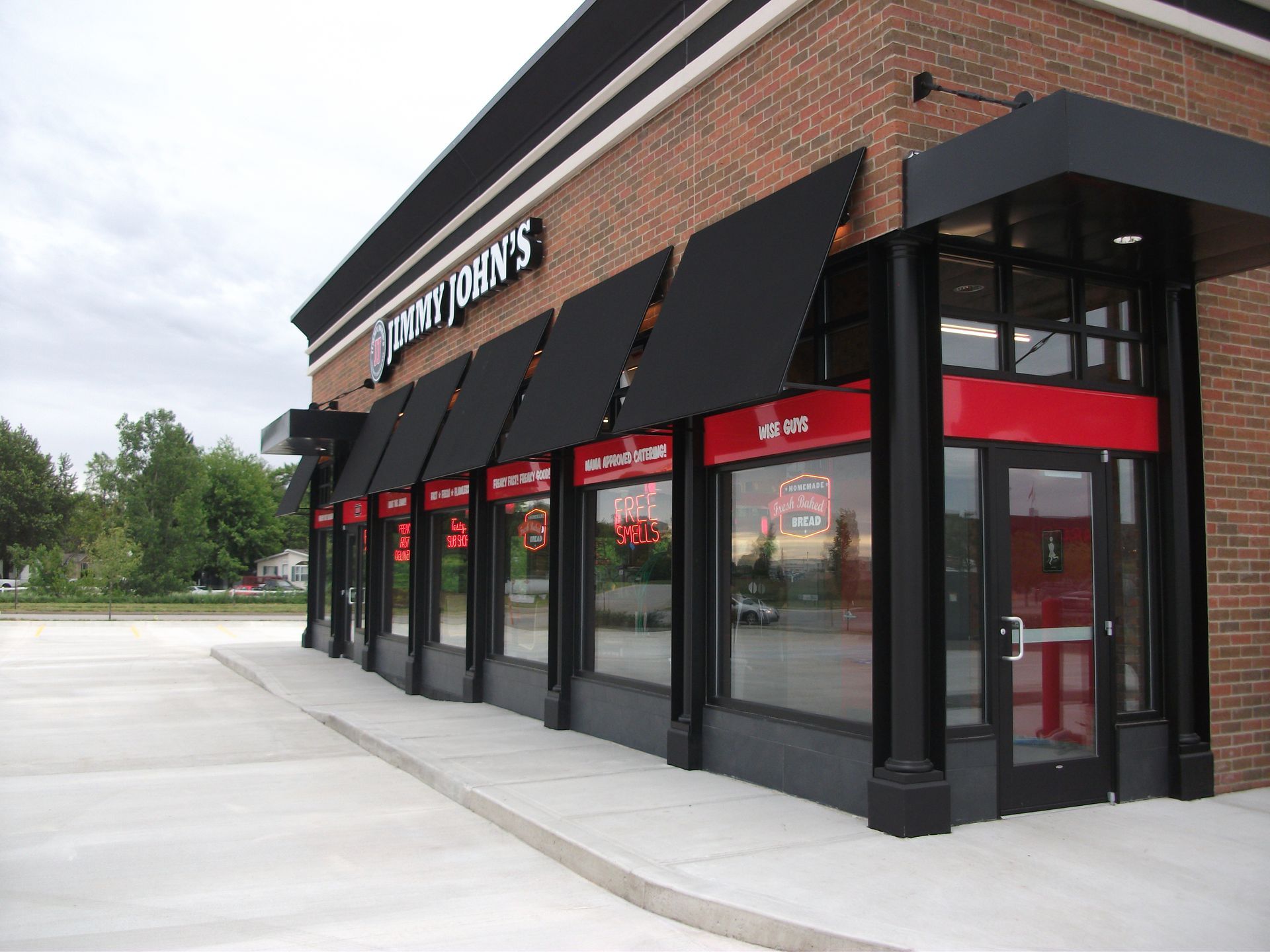 A brick building with black awnings and a red door