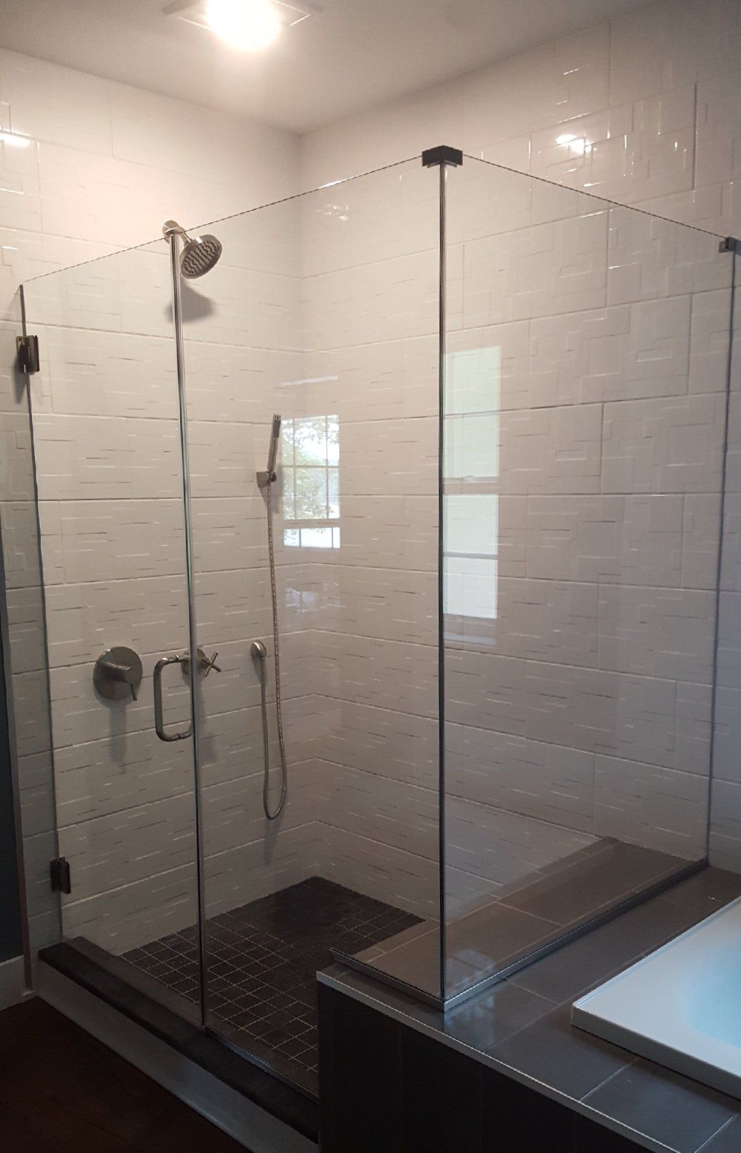 A bathroom with a walk in shower with a glass door.
