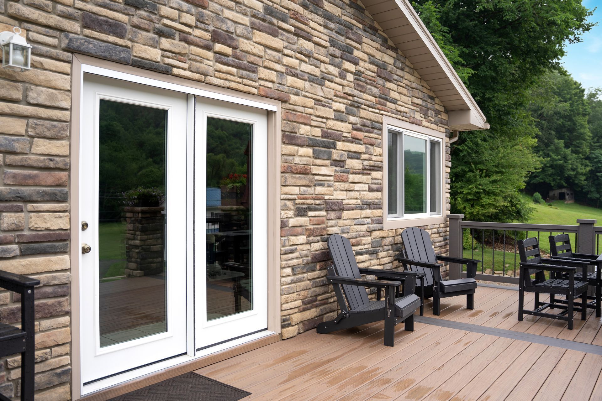 A house with a deck and chairs in front of it.