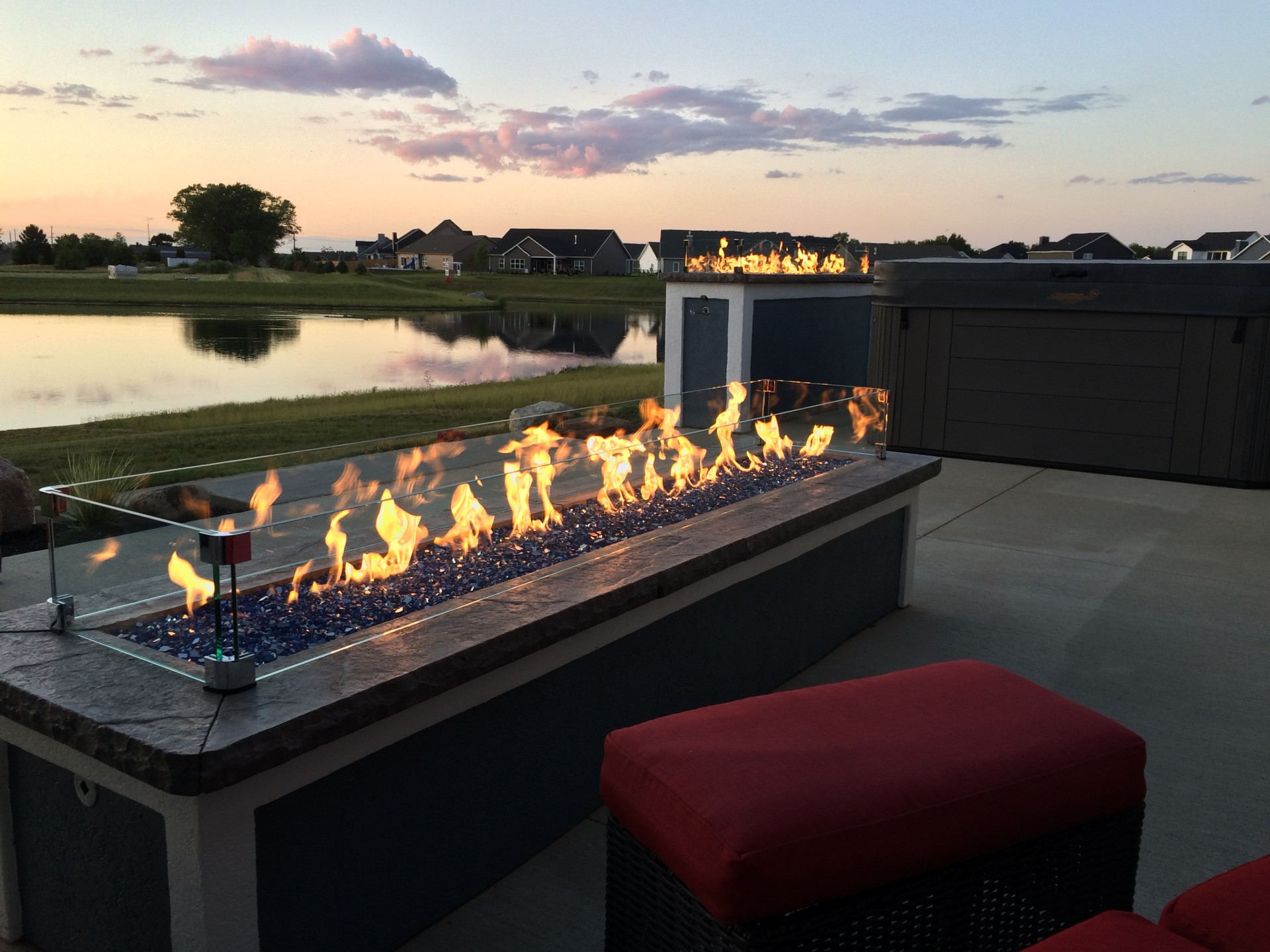 A fire pit on a patio with a hot tub in the background