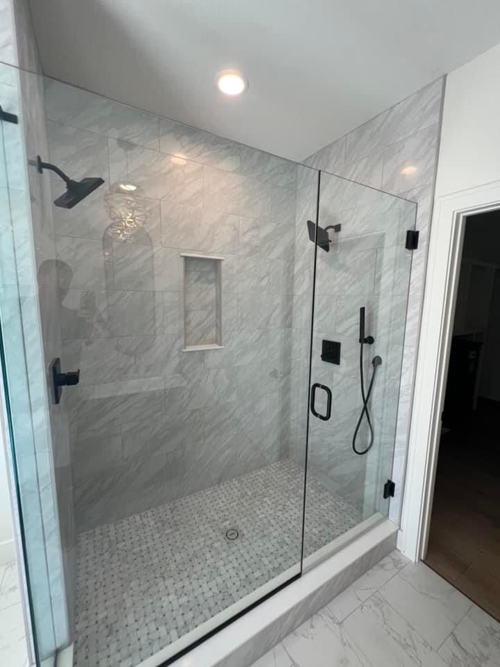 A bathroom with a walk in shower with a glass door.