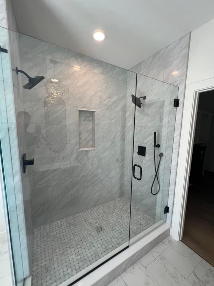 A bathroom with a walk in shower with a glass door.