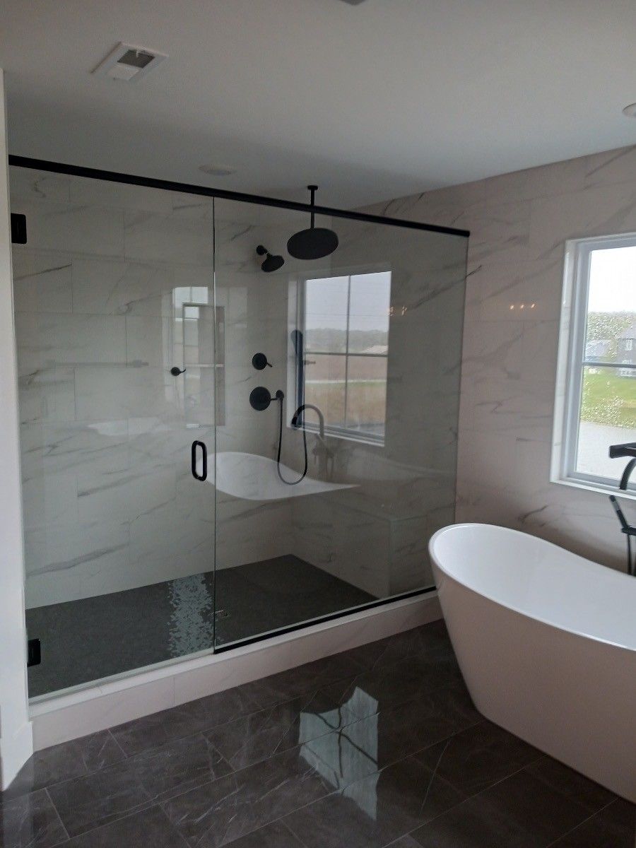 A bathroom with a tub , shower , and window