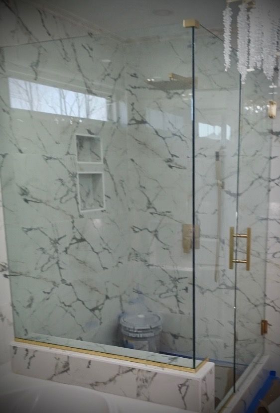 A bathroom with marble walls and a glass shower door.