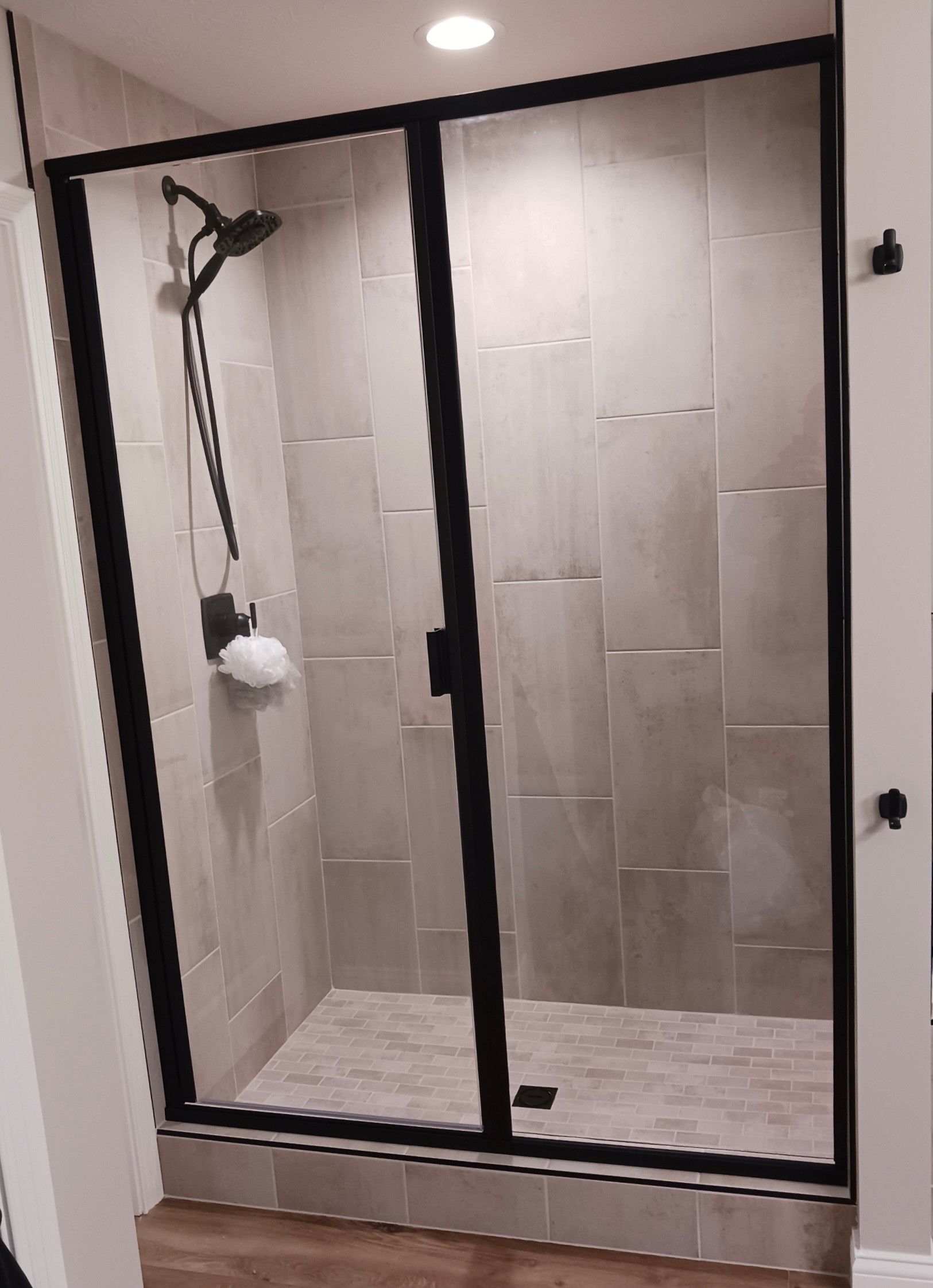 A shower stall with a black frame and sliding glass doors.