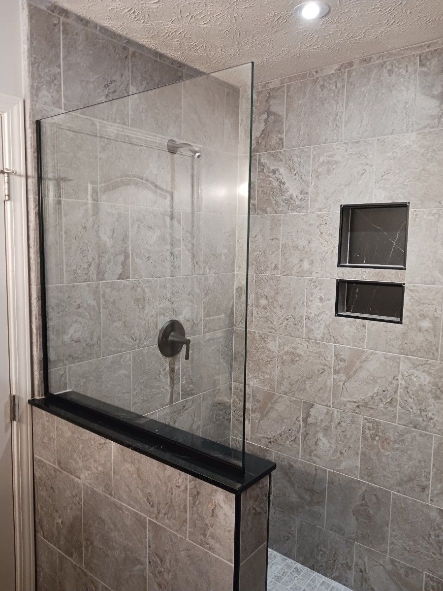 A bathroom with a walk in shower with a glass door.