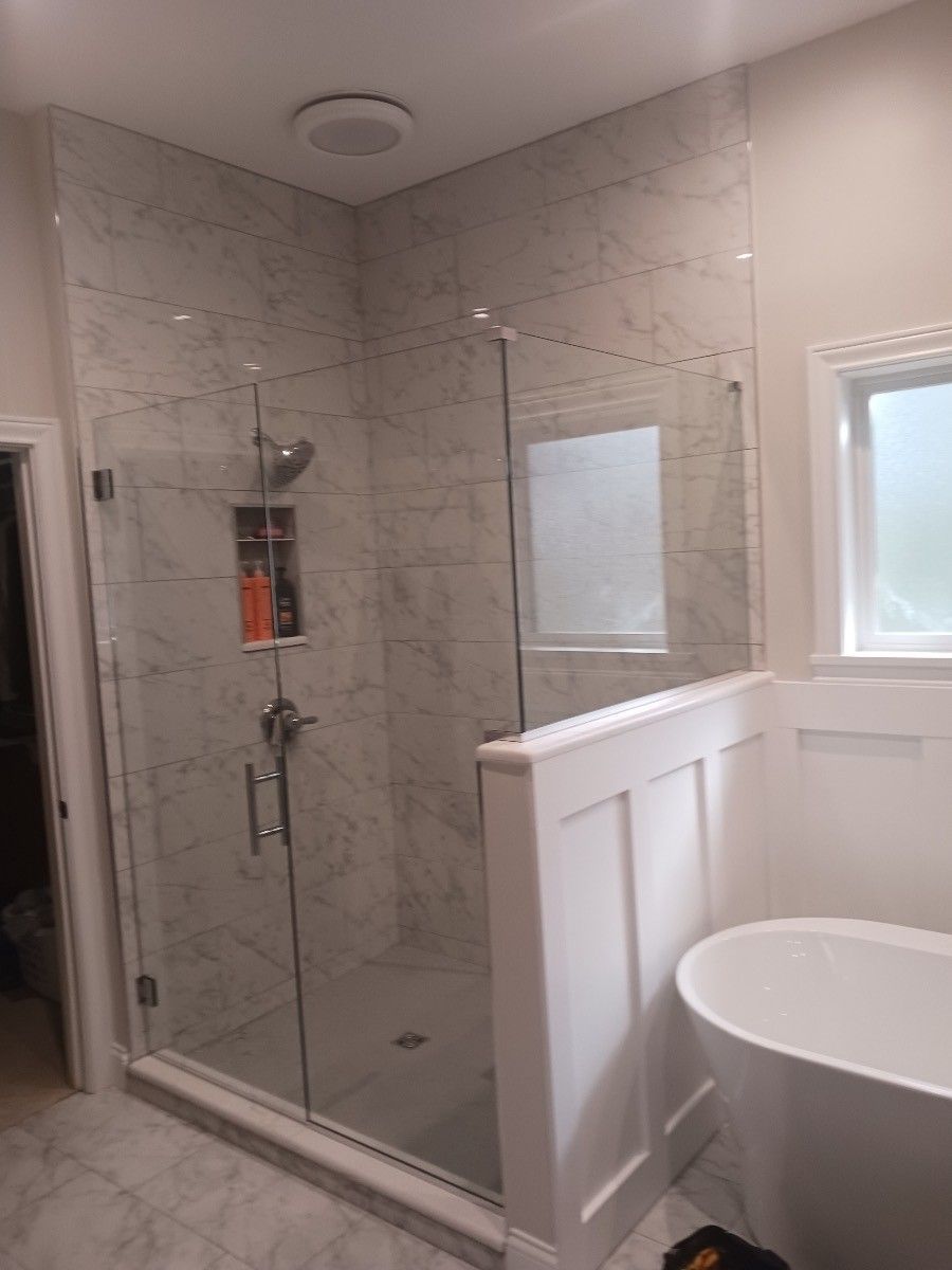 A bathroom with a tub and a shower with a glass door.