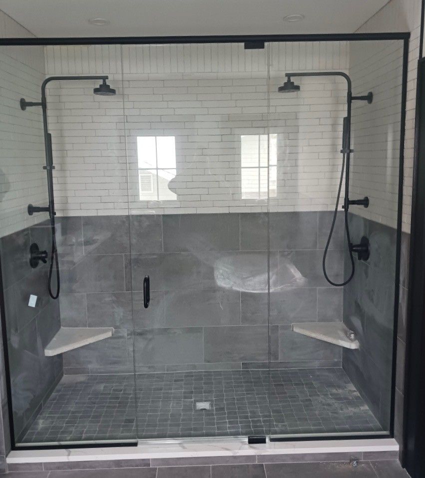 A bathroom with two showers and a glass shower door.