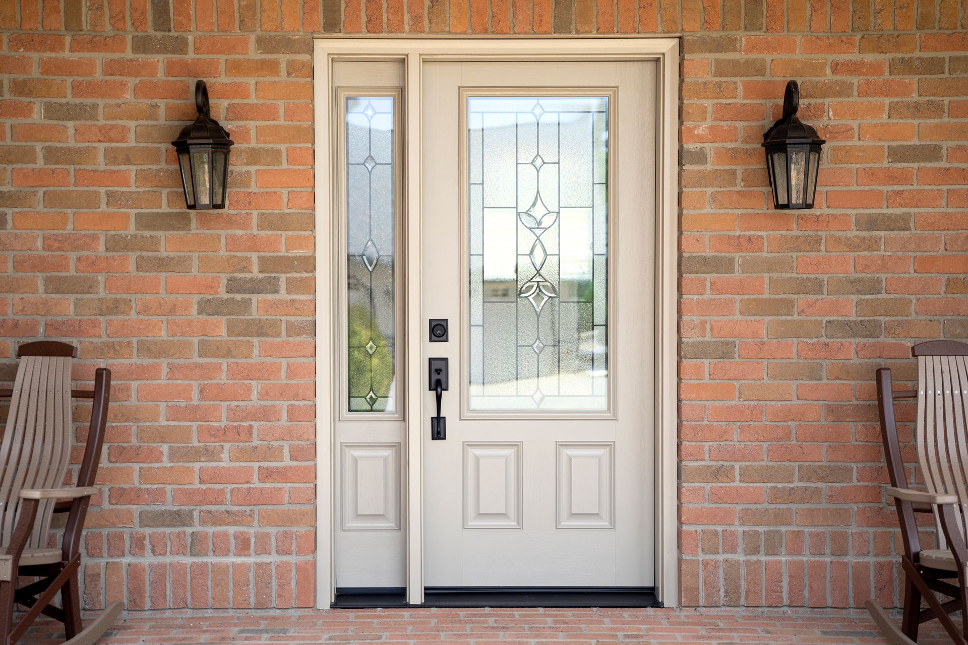 A white door is on a brick wall next to a porch with rocking chairs.
