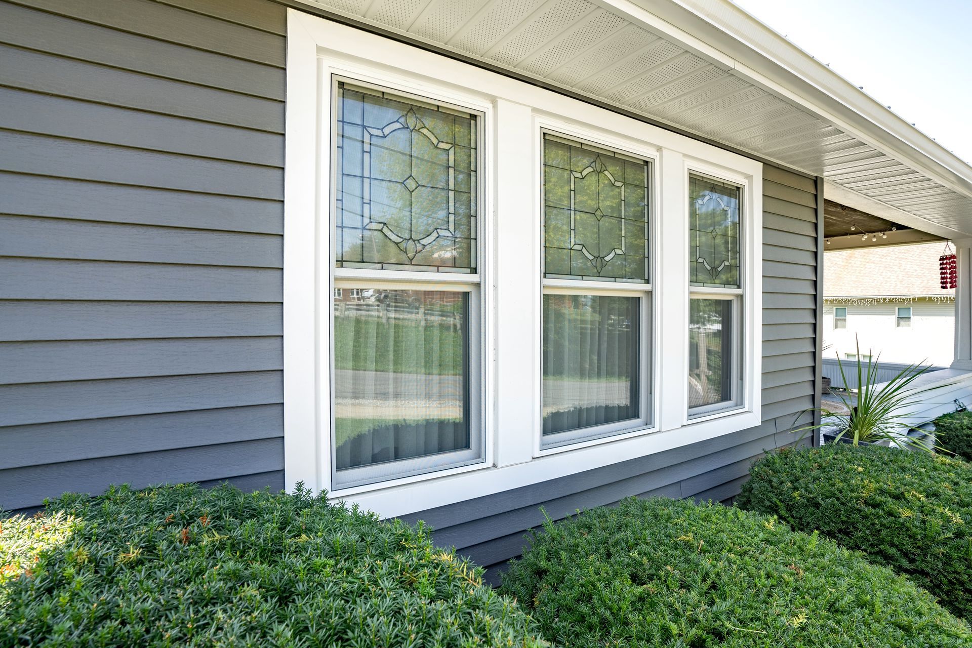 A house with a lot of windows and bushes in front of it