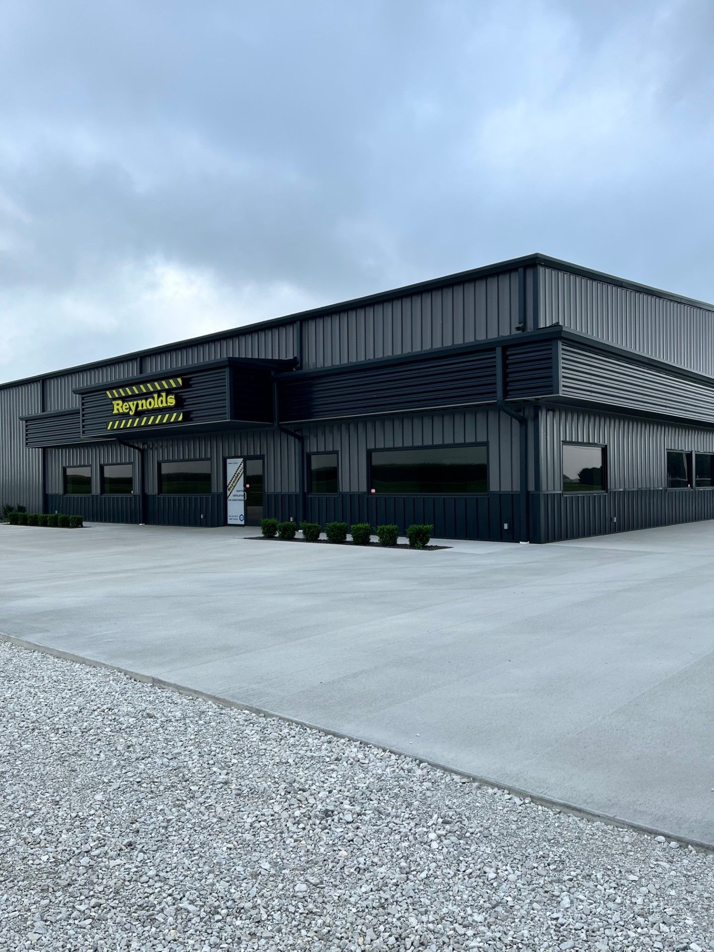 A large metal building with a gravel driveway in front of it.