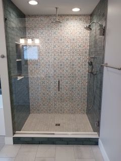A bathroom with a walk in shower with a glass door.