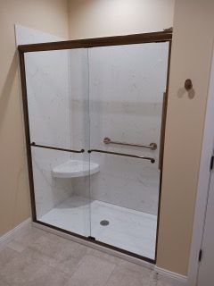 A bathroom with a sliding glass shower door and a bench.