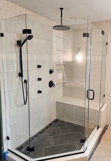 A bathroom with a walk in shower with a black shower head.